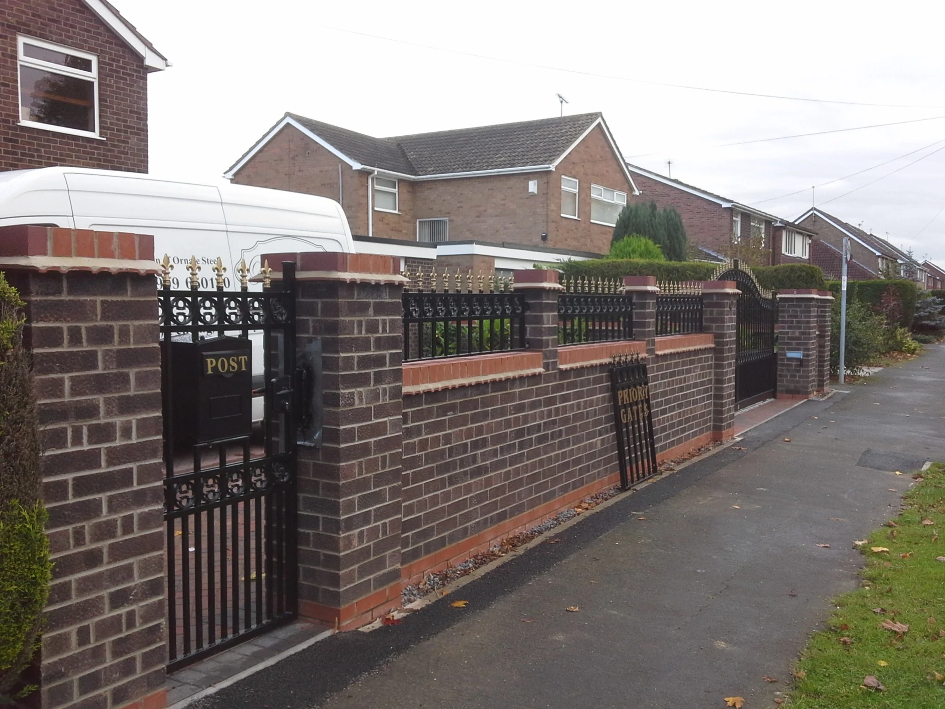 a brick wall with a black gate and a white roof